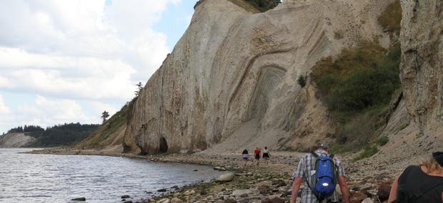 Folk der går på stranden, med en molerklint i baggrunden