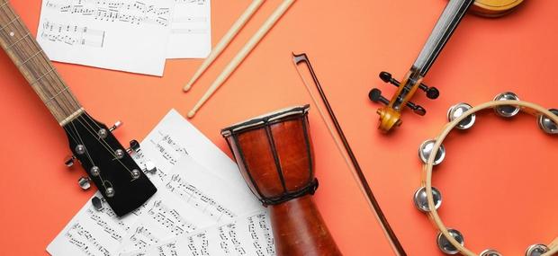En violin, tromme, guitar, en bue til violin samt nodepapir.