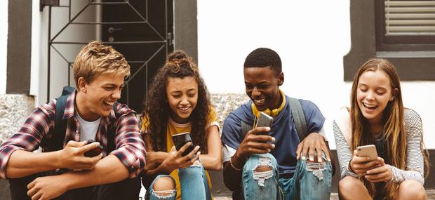 Unge sidder fælles og griner af det der foregår på deres mobiler