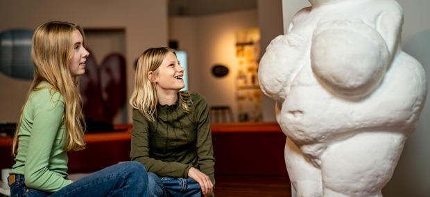 Piger kigger på statue af Venus fra Willendorf.