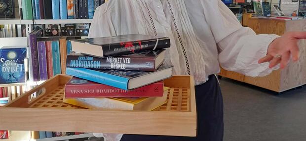 En bibliotekar står med en bakke fyldt med bøger, og byder velkommen.