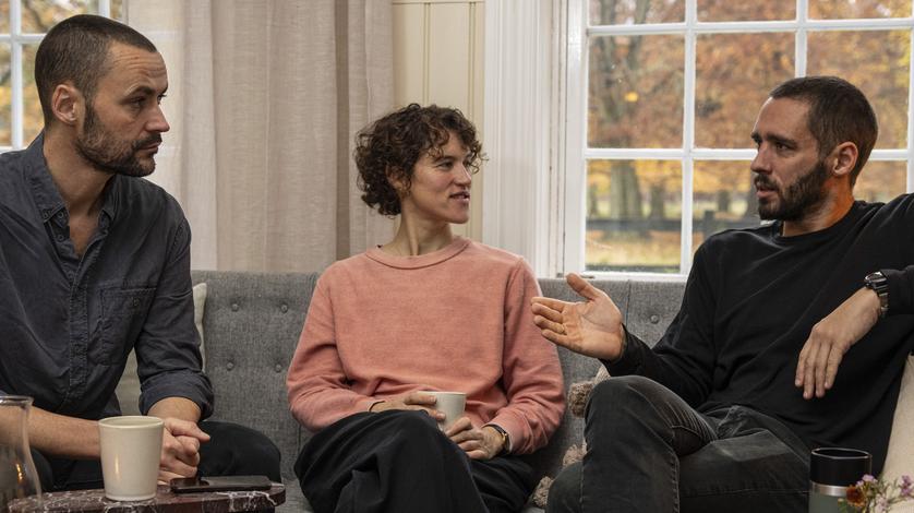 Tre personer sidder og snakker i en sofa
