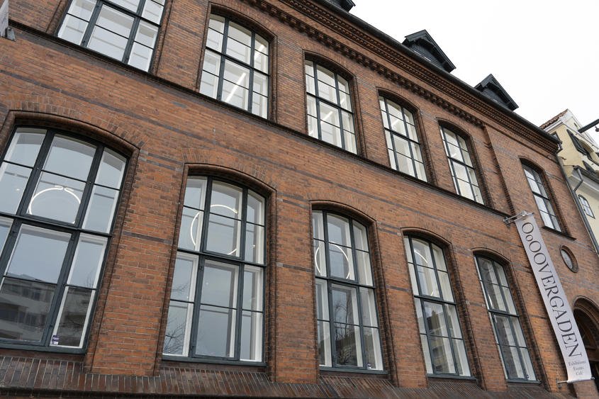 Billede af Overgadens facade. Kunsthallen breder sig over to etager i en gammel fabriksbygning lige ved Christianshavns kanal, nær torvet.