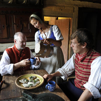 Madmor skænker op for husbond og karlen.