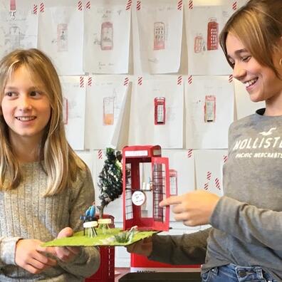 To piger med en rød telefonboks de har lavet.