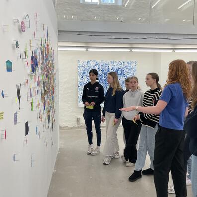 En klasse går rundt sammen med en kunstformidler og snakker om udstillingerne