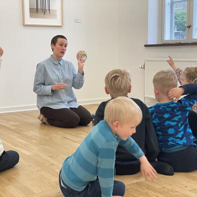 En flok børn sidder i udstillingen og snakker om kunsten.