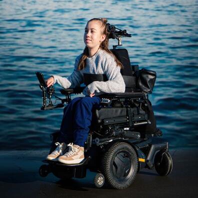 En ung kvinde i kørestol ude ved havet