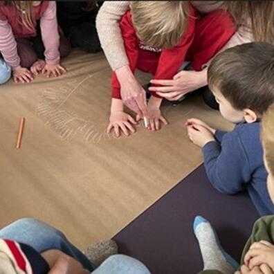 Børn tegner omrids af sig selv på et stort papir på gulvet.