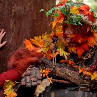 En kvinde klædt ud som et træ i skoven.