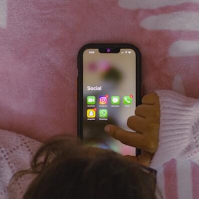 Et barn der ligger med sin mobil og kigger på sociale medier.