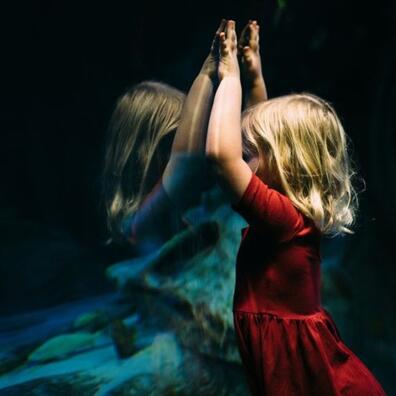 En pige kigger gennem glas og glasset afspejler hende