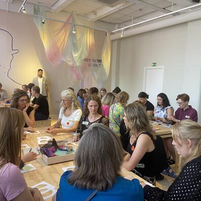 en stor gruppe sidder fokuseret i et værksted