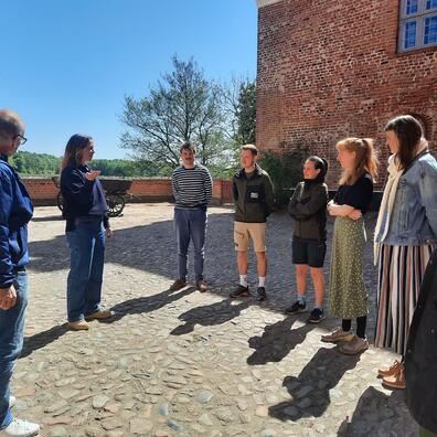 en gruppe står og lytter til en underviser